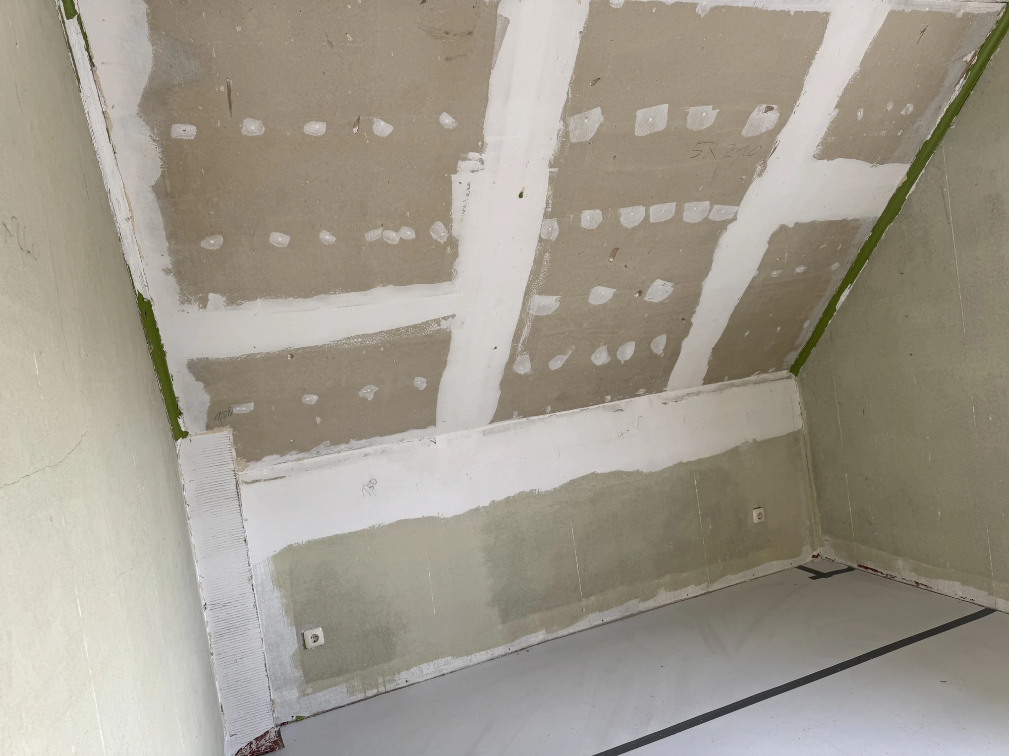 Dachgeschossraum mit Dachschräge aus Trockenbauplatten, deren Fugen und Schraubenköpfe weiß verspachtelt sind