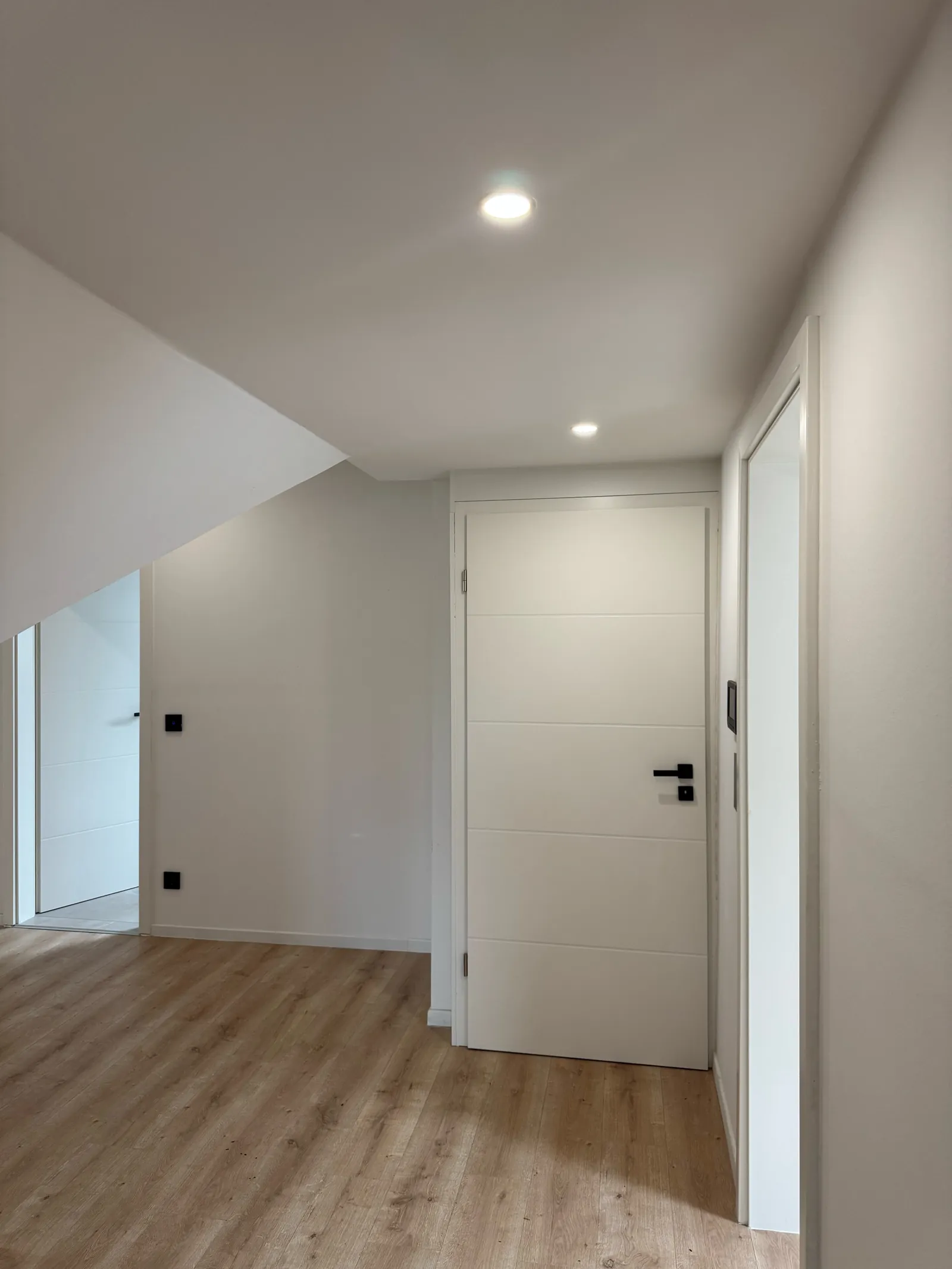 Fertiger Flur im Dachgeschoss mit weißen Innentüren, Einbauspots und Boden in Holzoptik
