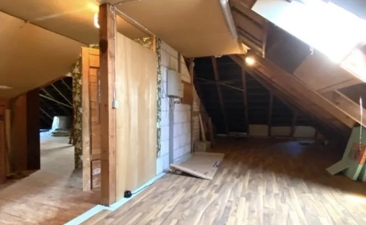 Dachboden vor dem Ausbau mit alten Holz- und Plattenverkleidungen, Dachfenster und altem Laminatboden