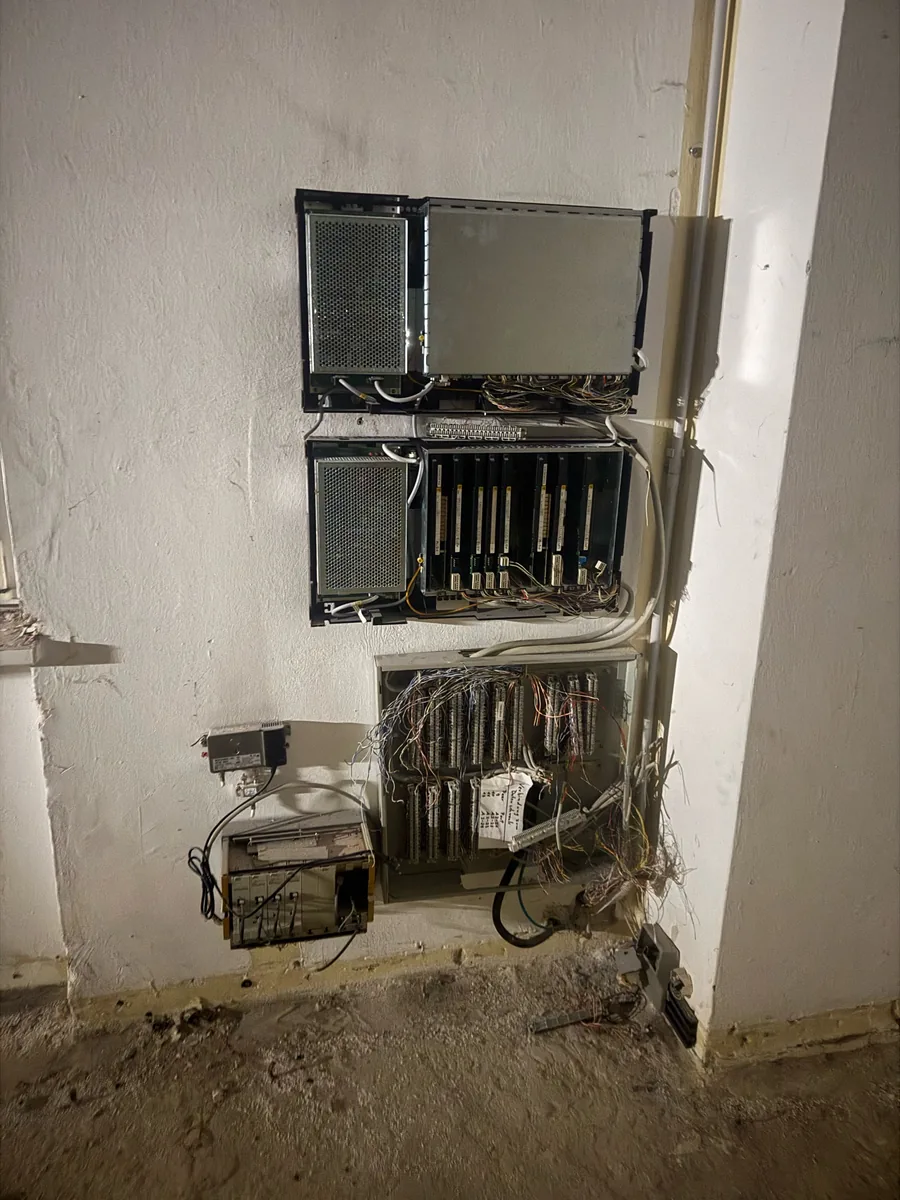 Alte Telefon- und Telekommunikationsverteilung mit offenen Leitungen an einer Kellerwand
